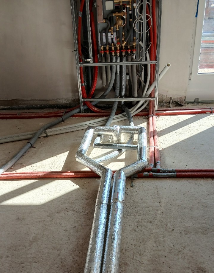 Rohrinstallation mit gedämmten Leitungen auf dem Rohfußboden